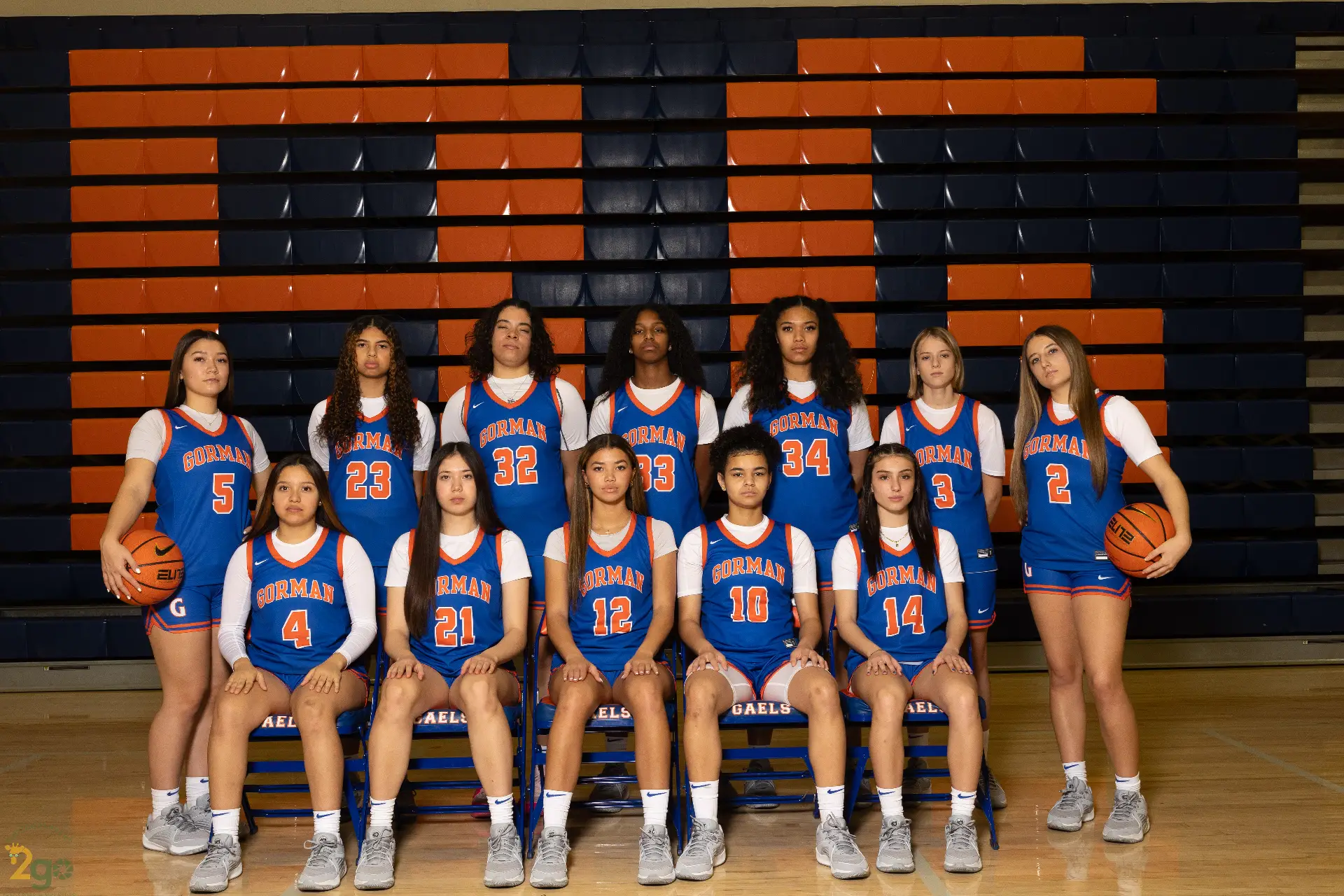 Group portrait of the Gorman High School girls basketball team in blue and orange uniforms, posing with basketballs.