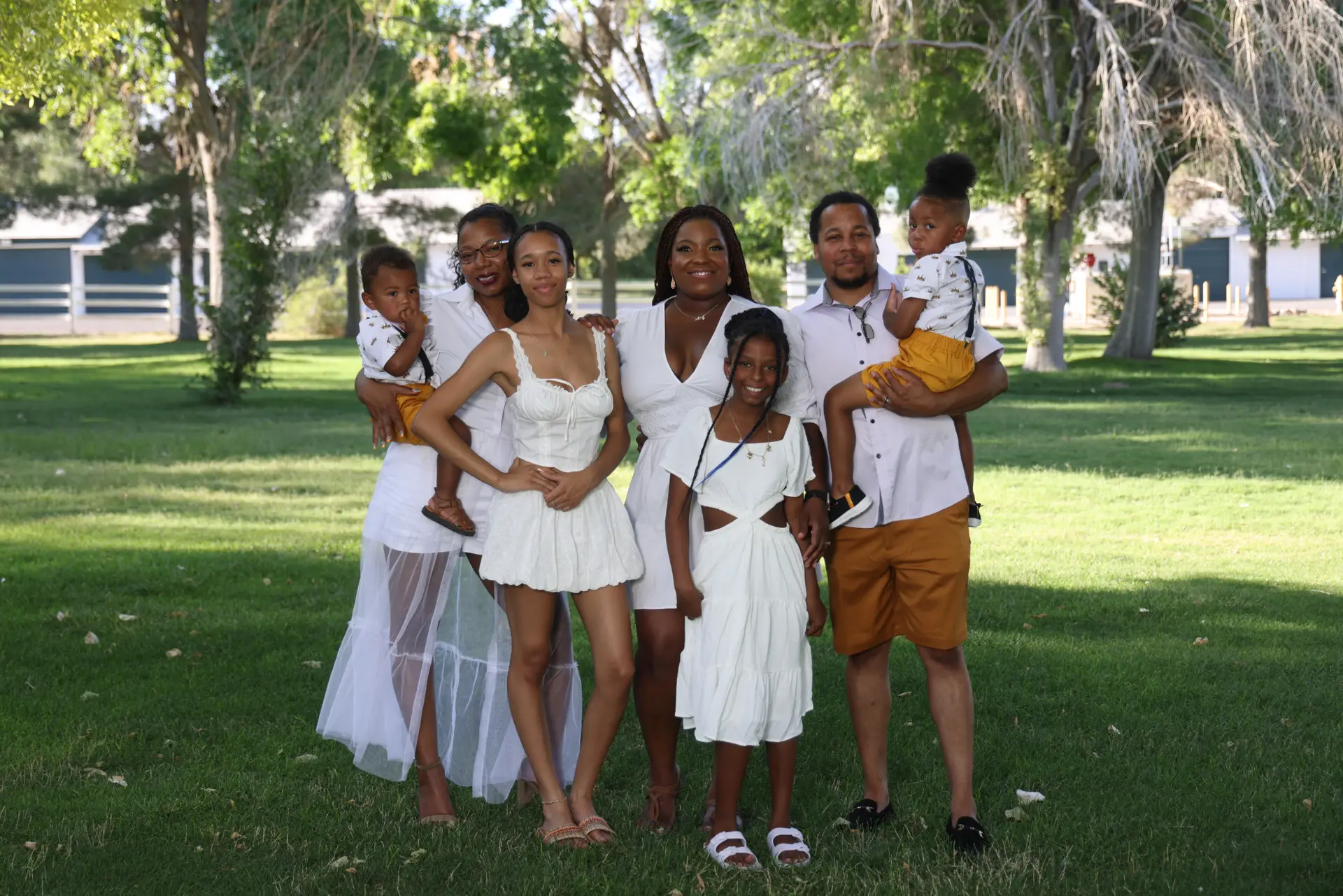 Group of six individuals posing together outdoors, wearing white and light-colored clothing.