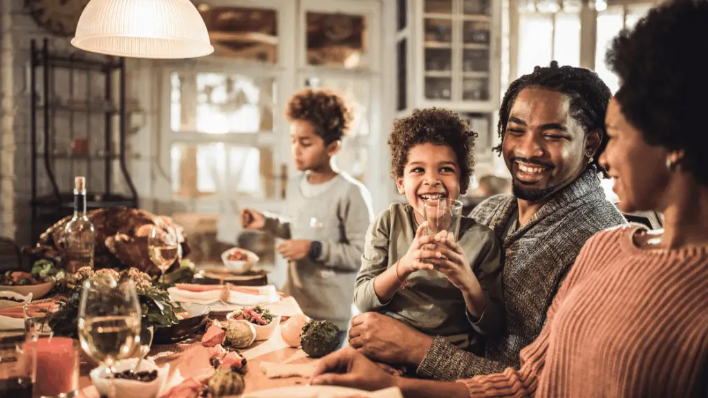 A family enjoying a meal together at a dinner table, with children and adults smiling and sharing moments.