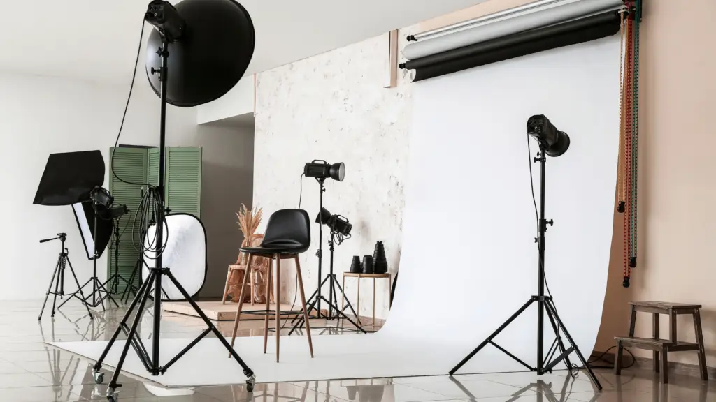 Photography studio with lighting equipment, backdrop, and a chair arranged for a photoshoot.